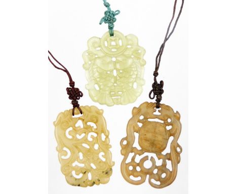 Three pendants, comprising a jade style pendant, of shaped form decorated with fish with a pierced upper section, 6cm high, a