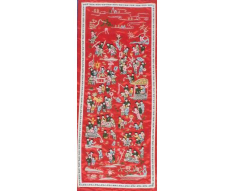 A 20thC Chinese silk embroidery panel depicting children playing, fishing and kite flying, etc., on a red ground, 84cm x 32cm
