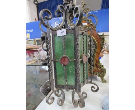 A wroght iron light fitting with green glass panels