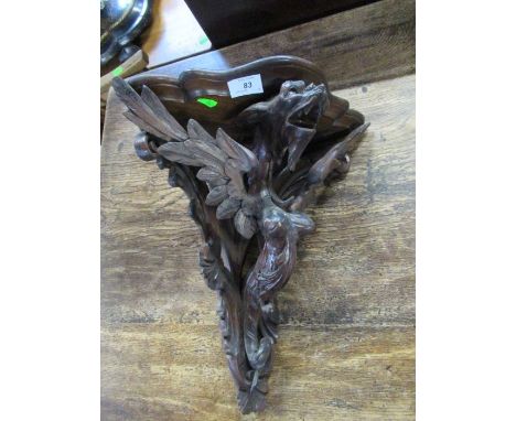 A carved oak corner wall bracket, decorated with a stylised mythical creature, width 16ins