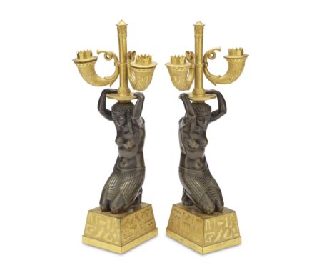 ​A pair of early 19th century French patinated and gilt bronze figural twin light candelabra in the Egyptian tasteAfter model