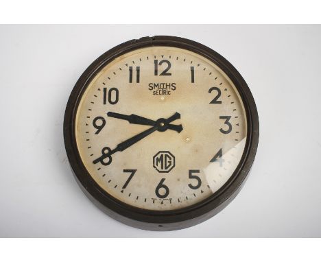 An 'MG' wall mounting clock by Smiths Sectric,circular brown Bakelite surround, white-painted dial with Arabic numerals and '