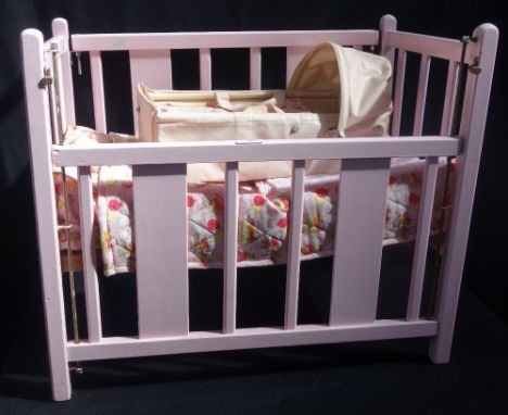 A TRI-ANG VINTAGE WOODEN DOLL'S COT painted pink and a carry-cot (2)