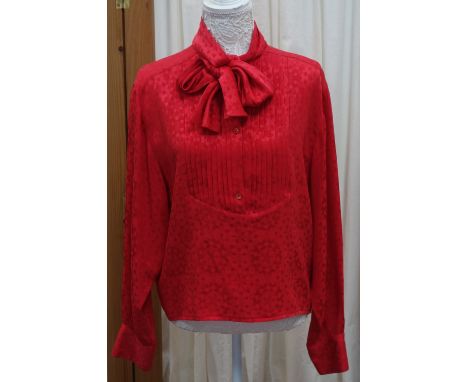 GUCCI: A lady's vintage red silk blouse C. 1980's with allover embossed detail fastened to the front with Gucci logo button a