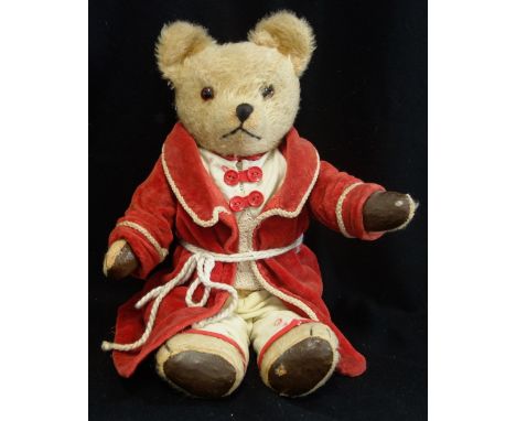 A VINTAGE PLUSH TEDDY BEAR with jointed limbs and leatherette pads, sporting a red dressing gown, 45cm high