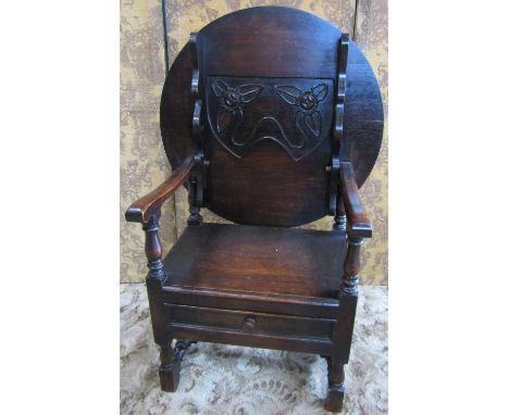 An oak monks seat/chair with stylised foliate carved floral back of circular form in the Art Nouveau manner above a single dr