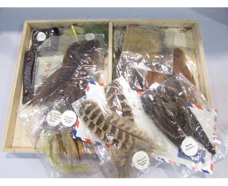 A Fly Fisherman’s Tying Box with a small clamp, tweezers, file, a selection of different coloured cottons, feather samples in