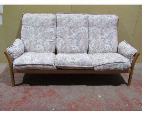 A pale Ercol three seat sofa with a pale coloured upholstery and blonde wood frame 