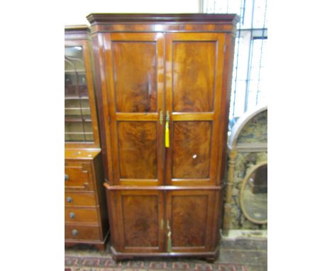 An impressive Georgian floor standing corner cupboard in mahogany, the upper section enclosed by two double panelled doors re
