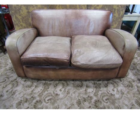 A leather covered tub two seat sofa, with club wing arms, in the Art Deco style, covered in weathered tan leather, 82cm high,