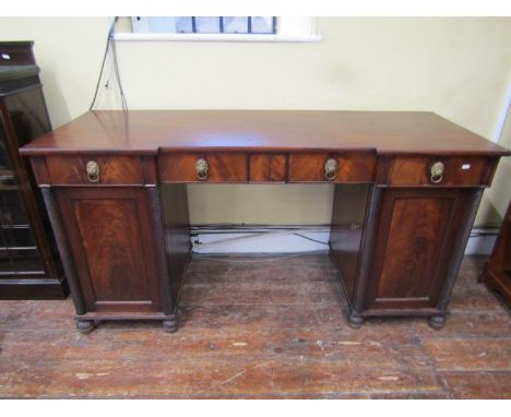 A William IV sideboard the central kneehole flanked by two cupboard doors with decorative fluted columns enclosing a shelf, u