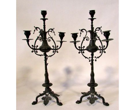 A tall pair of 19th century bronze five light candelabra, with ebonised finish, scrolling and swept branches, raised on tripo