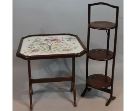 A 1920's oak cake stand, in three sections with articulated centre, on shaped supports, (when closed) 90cm high, 31cm wide, 1