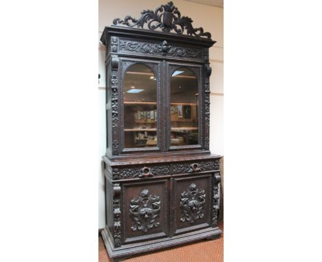 A heavily carved 19thC Continental oak bookcase, with elaborate shield scroll and floral cornice above a carved frieze raised