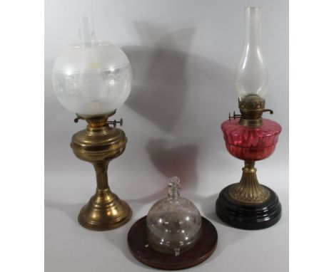 An early 20thC cranberry and clear glass oil lamp, with clear funnel, shaped reservoir, inverted stem and ebonised foot, 59cm