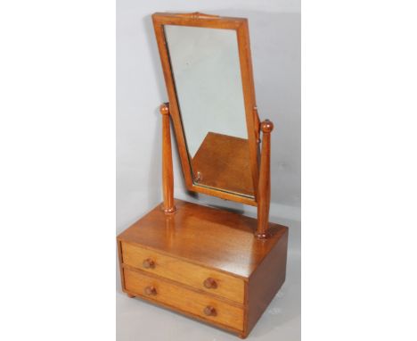 A light oak table mirror, the rectangular glass with plain outline broken by mouldings, flanked by cylindrical columns raised