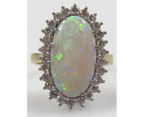 An 18ct gold opal and diamond dress ring, with central elongated oval opal, surrounded by tiny diamonds, in a platinum settin