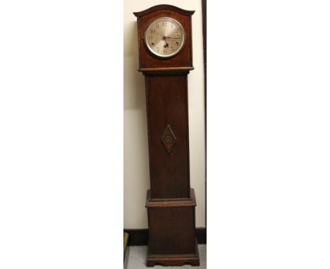 A 1920's oak cased granddaughter clock, the 16cm dia. Arabic dial with three winding holes in a shaped case, on compressed br