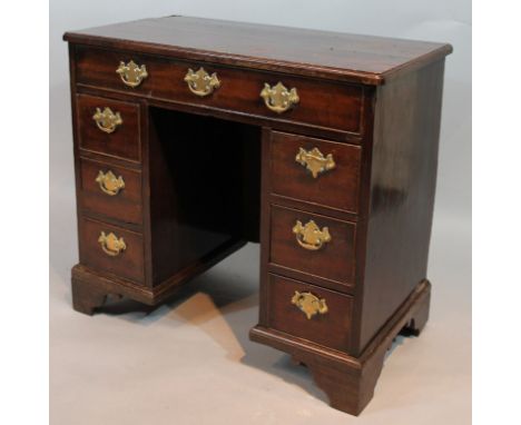 A principally George III mahogany kneehole desk, the rounded overhanging top raised above one frieze drawer and six pedestal 