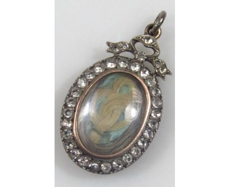 An early 20thC portrait locket, set with various white paste stones, with locket of hair to centre, in silver frame, 3.5cm hi