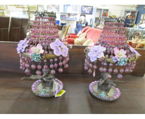 A pair of metal monkey candle lighters with shades, composed of diamante bows, faceted iridescent coloured glass beads and fa