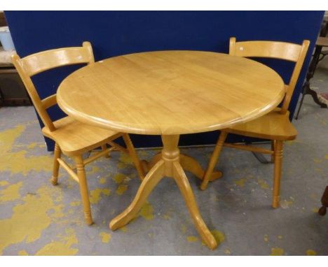 A small circular pine tripod kitchen table and two matching pine chairs. 