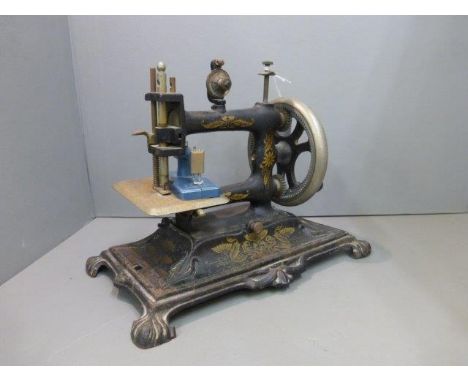 An early Victorian cast iron hand sewing machine NR12 with German instruction manual and a tool kit; also a miniature working