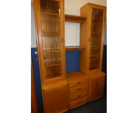 A good quality Ercol light elm three-part display cabinet with four small central drawers flanked by cupboards enclosed by tw