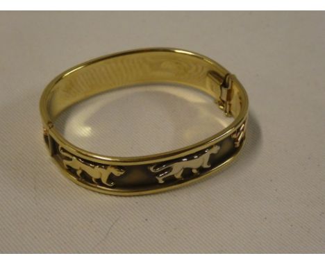 A 9ct gold oval bangle decorated with tiger emblems (24.2g)