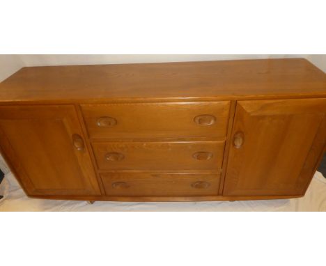 An Ercol light elm sideboard with three central drawers flanked by cupboards enclosed by two panelled doors 61" long