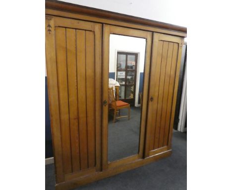 A Victorian New Zealand ash triple wardrobe with sliding trays, internal drawers and hanging compartment enclosed by two pane