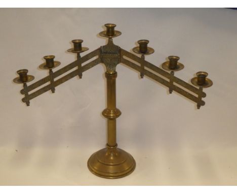 A brass rise and fall adjustable candle lamp with seven candle sconces on a tapered stand