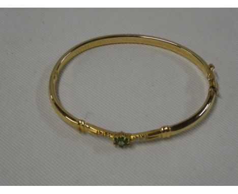 An 18ct gold oval bangle with floral mount set six emeralds and five diamonds (10.4g)