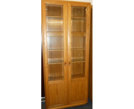 A good quality Ercol light elm display cabinet with shelves enclosed by two glazed doors 84" high x 36" wide