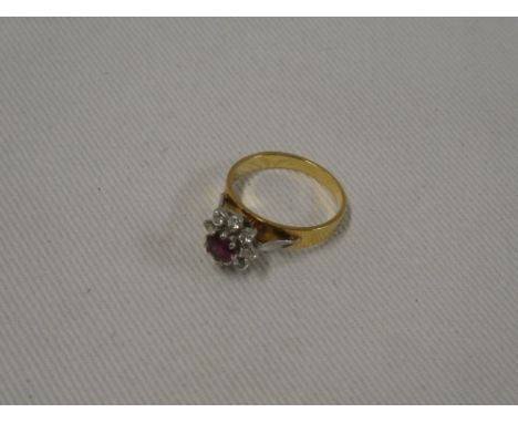 An 18ct gold dress ring set central ruby surrounded by eight small diamonds