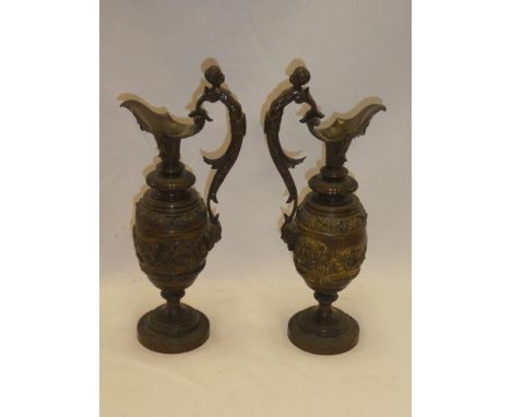A pair of old bronze ornamental ewers with raised cherub figure and mask head decoration, 13" high