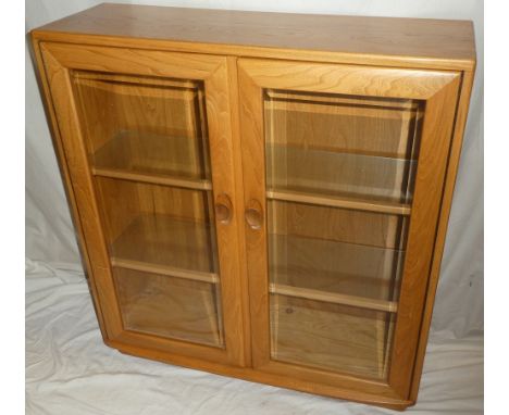 An Ercol light elm display cabinet with glass shelves enclosed by two glazed doors 39" high x 36" wide