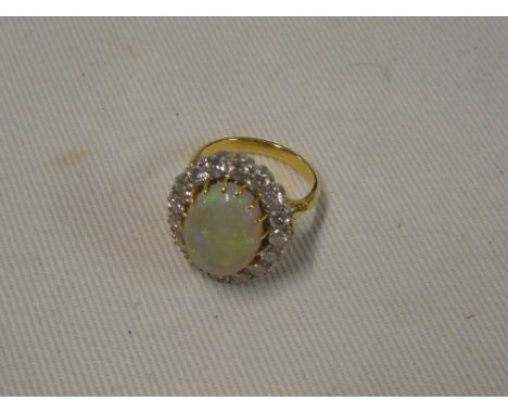 An 18ct gold dress ring set central opal surrounded by sixteen diamonds