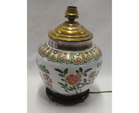 A Chinese pottery circular tapered vase with painted floral decoration, adapted as a table lamp with brass mounts and wooden 