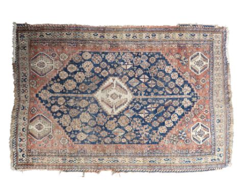 A blue ground nomadic rug with cream geometric central medallion, terracotta spandrels on floral patterned ground within geom