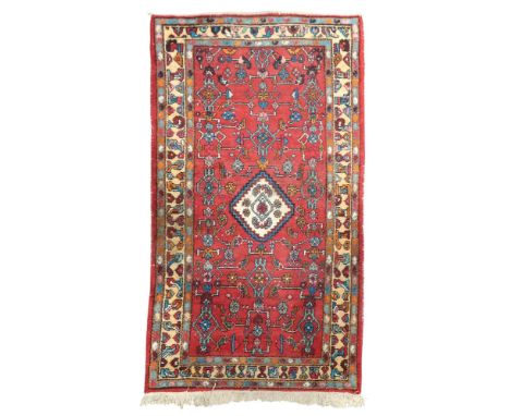 A red ground Hamadan rug with cream central medallion on geometric patterned ground within beige geometric border, 190cm long