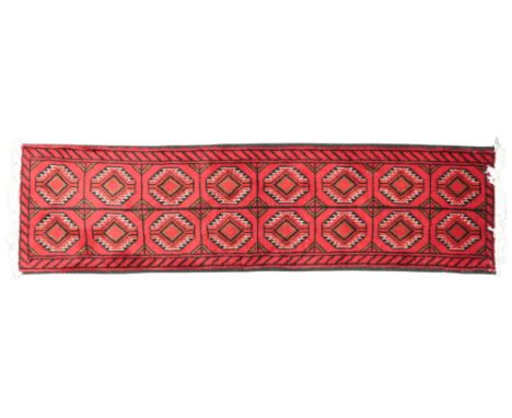 A red ground Turkoman runner with multicoloured geometric patterned ground, 201cm long x 55cm wide Condition Report:Available