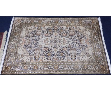 A dark blue ground fine silk Kashmiri rug with cream central medallion and matching spandrels on floral patterned ground with