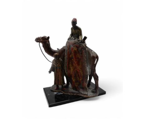 A cold painted spelter table lighter in the style of Franz Bergman, modelled as two carpet sellers and camel, on black glass 