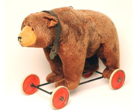 A Steiff bear on wheels, mid 20th century, with straw stuffed body, covered in brown plush, with pull ring growl, black/amber