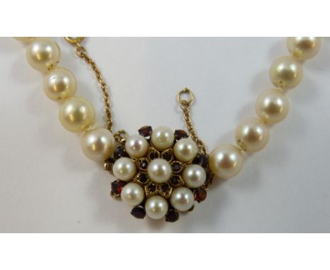 A single row cultured pearl necklace, composed of 86 beads of 7 mm diameter, to a garnet and cultured pearl clasp, length 73c