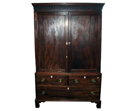 A George III mahogany linen press, the moulded cornice with lambrequin frieze over two panelled cupboard doors, enclosing an 