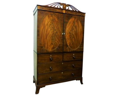 An early 19th century mahogany linen press, with pierced scrolling pediment over an inlaid frieze, in turn over two oval pane