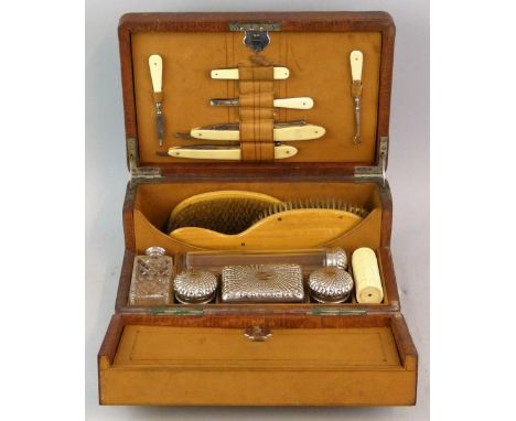 A late Victorian gent's travelling toilet set with reptile skin leather cover, of rounded oblong form, the hinged lid with re