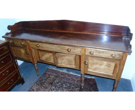 A Georgian Mahogany Irish Sideboard of Narrow Proportions; with three frieze drawers over four panelled doors, on ring turned
